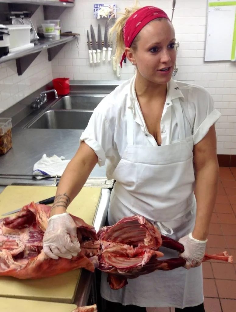 Chef Roxanne Spruance preparing meat in a professional kitchen