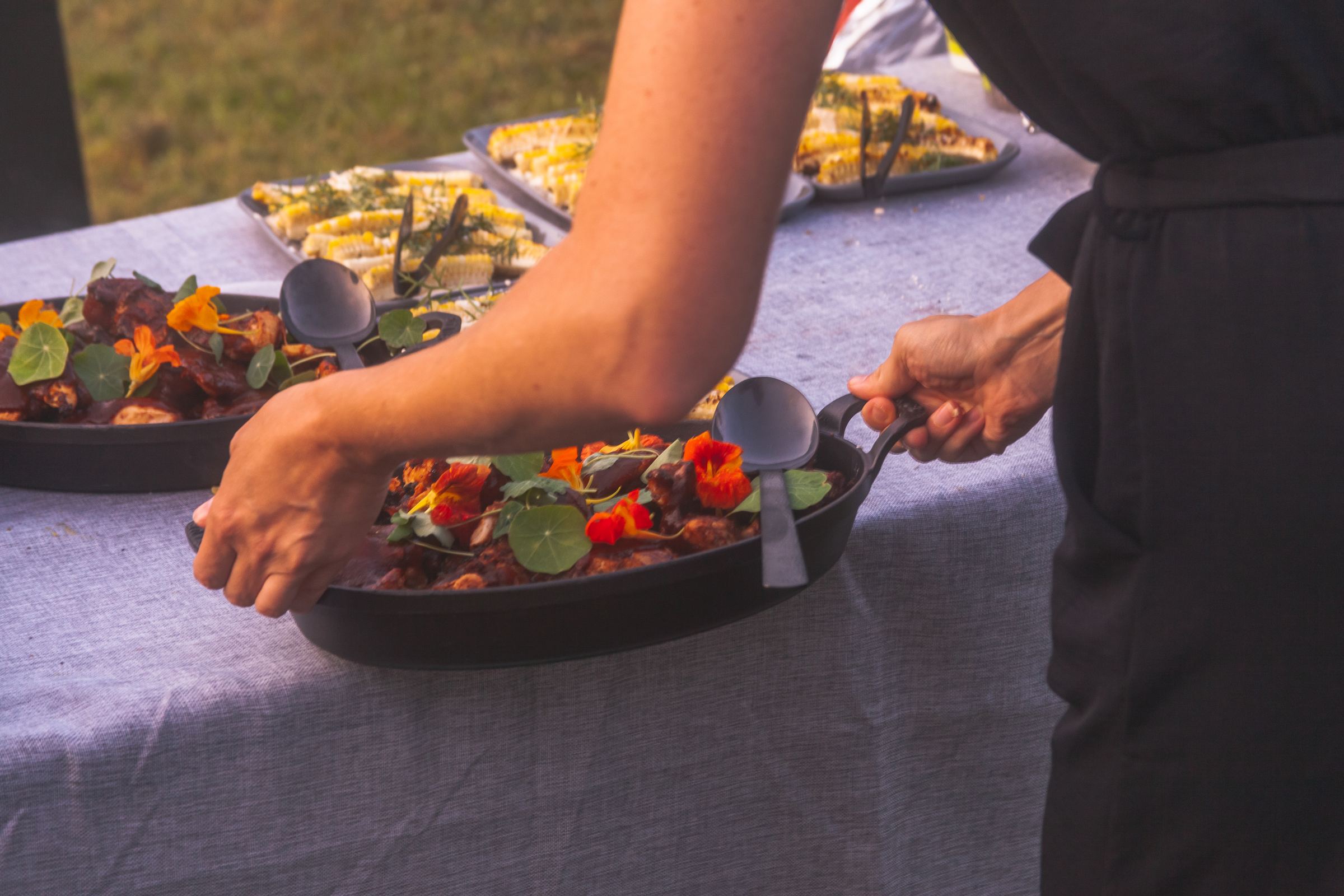 Chef plating cast iron-roasted dish with edible flowers